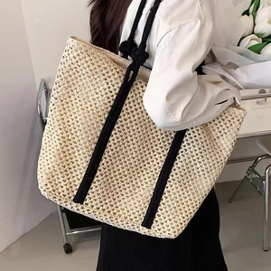 Large beige woven straw tote bag with black rope handles for beach or casual use