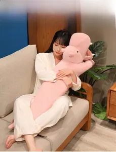 Asian model holding a long pink plush hippopotamus pillow in a cozy home setting