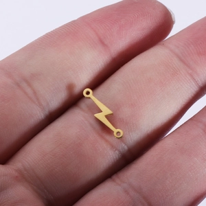 Macro shot of a tiny golden lightning bolt connector charm held in a person's palm