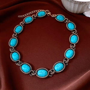 Detailed close-up of vintage bronze necklace with blue oval stones on brown silk fabric