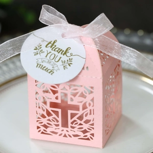 Detail van roze lasergesneden geschenkdoos met kruis, wit lint en bedankkaartje