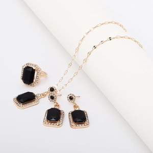 Detail of elegant gold jewelry set featuring rectangular black gemstones and tiny diamonds
