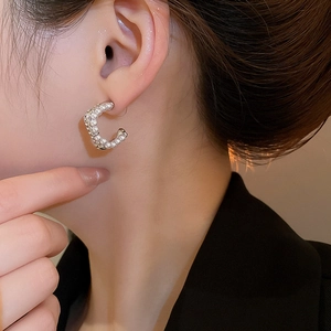 Detailed close-up of C-shaped silver pearl earrings featuring elegant vintage crystals