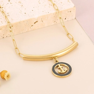 Detailed macro view of a gold anchor pendant necklace on a decorative stone base