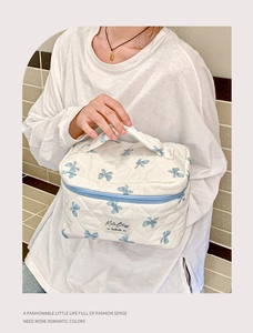 Détail de la trousse de maquillage matelassée blanche avec motifs de nœuds bleus