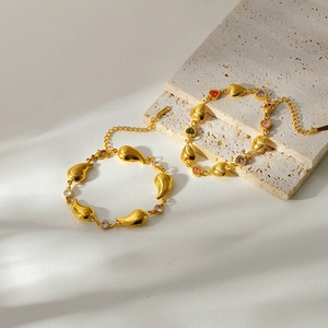 Détail de bracelets plaqués or avec pierres colorées en forme de cœur et maillons gouttes