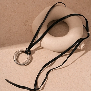 Collana minimalista con pendente ad anello d'argento e cordino di cuoio nero su pietra