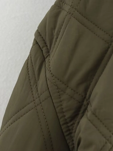 Nahaufnahme der olivgrünen Steppjacke mit detaillierten Rautensteppungen und winddichtem Stoff