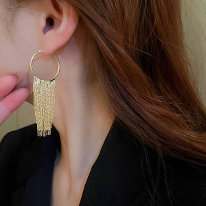 Close-up of golden tassel hoop earrings on model featuring long dangling chains