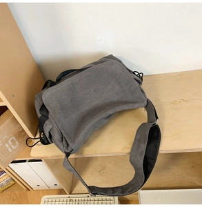 Macro detail of the grey canvas messenger bag with adjustable wide shoulder strap on a shelf