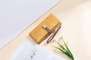 Detail of vintage matte leaf wallet with metal buckle and wrist strap in ginger yellow