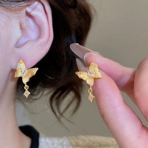Detail of 24K gold plated butterfly earrings with zircon stones and matte metal texture