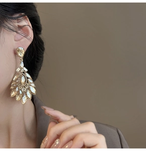 Close-up of champagne teardrop earrings with marquise crystals on a model