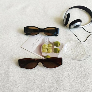 Detailed top view of retro cat eye sunglasses in black and tortoiseshell on a textured surface