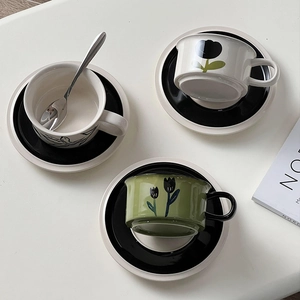 Overhead view of vintage hand-painted floral ceramic coffee cups and saucers set on a desk