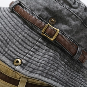 Dettaglio macro di cappello bucket in tela lavata con cinturino in pelle e fibbia