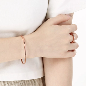 Detail of rose gold stainless steel minimalist round bracelet and matching ring on model