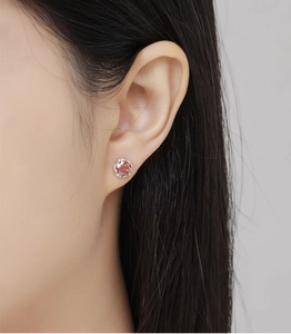 Detailed close-up of a pink round gemstone stud earring in a silver claw setting