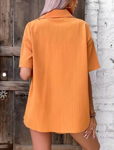 Detail showing the vertical texture and back drape of an orange short sleeve lapel shirt