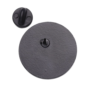 Rear view of round metal badge showing matte black texture and secure rubber clutch