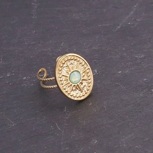 Detail of vintage golden sunburst ring with light green stone and rope textured band