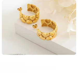 Detail of 18K gold plated heart splice hoop earrings on minimalist stone display