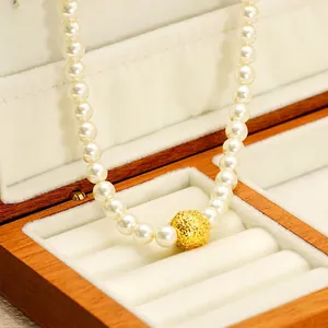 Elegant 18K gold-plated pearl necklace featuring a central hollowed luck bead on velvet