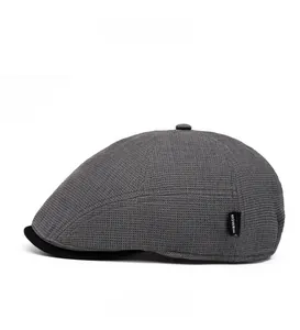 Close-up of grey waffle fabric flat cap featuring a black brim and side brand label