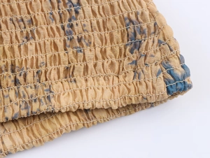 Detailed macro view of yellow smocked fabric with blue floral print and elastic stitching
