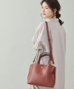 Detail of reddish-brown PU leather tote bag with gold hardware and adjustable strap