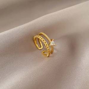 Detail of gold double-layer ring with triangle zircon and pave stones on silk background