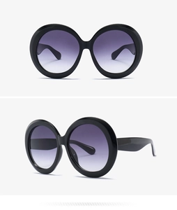 Detail view of oversized round sunglasses with purple gradient lenses and black frame