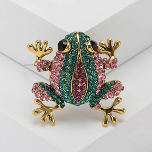 Close-up of a frog brooch featuring colorful rhinestones on a gold metal frame