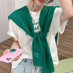 Detail view of emerald green knit shawl with hollow crochet and letter leather patch