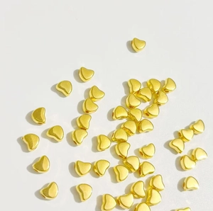 Perles en forme de cœur dorées en ABS pour la création de bijoux DIY sur fond blanc