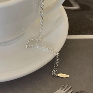 Detailed close-up of S925 sterling silver chain with authenticity tag on a white cup