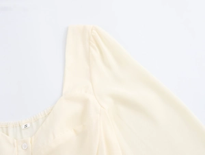 Close-up of the square neckline and puff sleeve detail on a beige French style dress