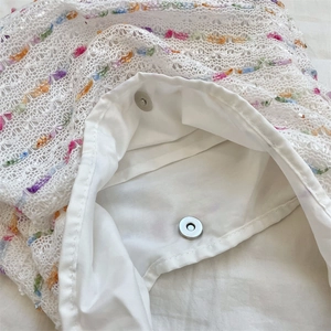 Detail of white crochet tote bag showing interior lining and silver magnetic snap closure