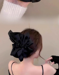 Dettaglio di una grande pinza per capelli con fiocco in raso nero dalla trama elegante