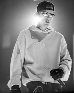 Artistic high-contrast view of a loose-fit grey hoodie with unique stitching detail