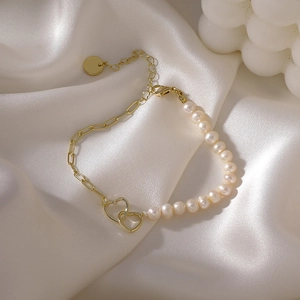 Detailed view of freshwater pearl and paperclip chain bracelet on white silk fabric