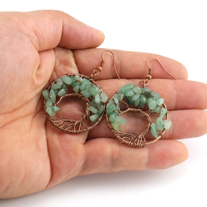 Handmade tree of life wire wrapped earrings with green natural crystal stones on palm