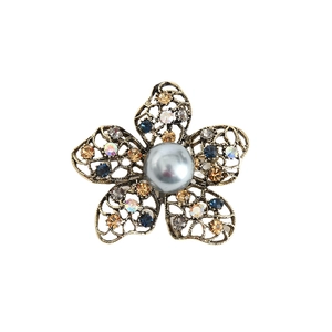 Vintage gold flower brooch with colorful crystals and gray faux pearl on white background