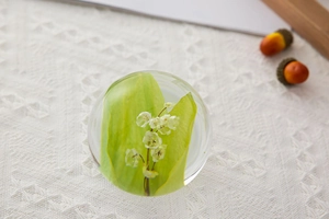 Detailed macro of crystal ball containing white lily flowers on a white lace fabric