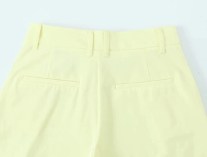 Detail of pale yellow wide leg trousers showing waistband loops and rear welt pockets