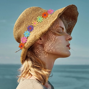 Close-up of brown straw sun hat featuring colorful daisy flower ornaments for girls