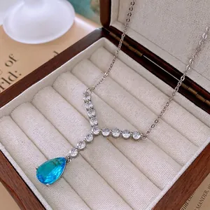 Elegant silver necklace with waterdrop blue zircon pendant on a beige velvet jewelry box