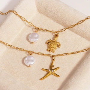 Golden titanium steel starfish and turtle anklets with pearls on a jewelry tray
