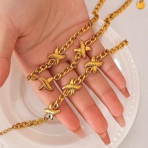 18k gold plated Cuban link bracelet with cross charms on a white display plate