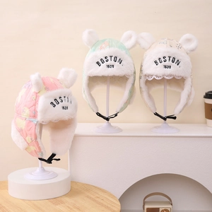 Detailansicht warmer Winter-Trappermützen für Kinder in Rosa, Grün und Beige.